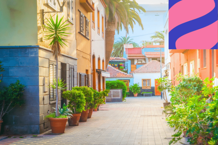 A sunlit, colourful alley with potted plants, palm trees, and Mediterranean-style buildings; a pink and purple abstract logo is in the upper right corner.