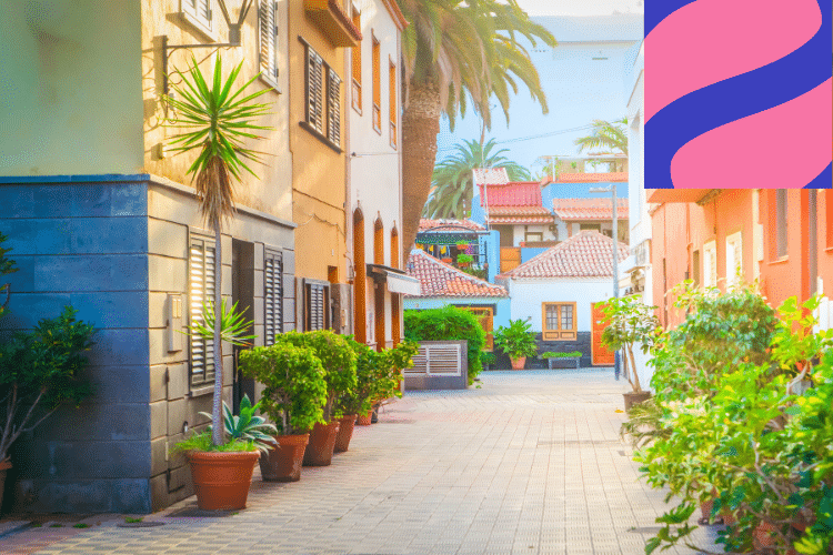 A sunlit, colourful alley with potted plants, palm trees, and Mediterranean-style buildings; a pink and purple abstract logo is in the upper right corner.