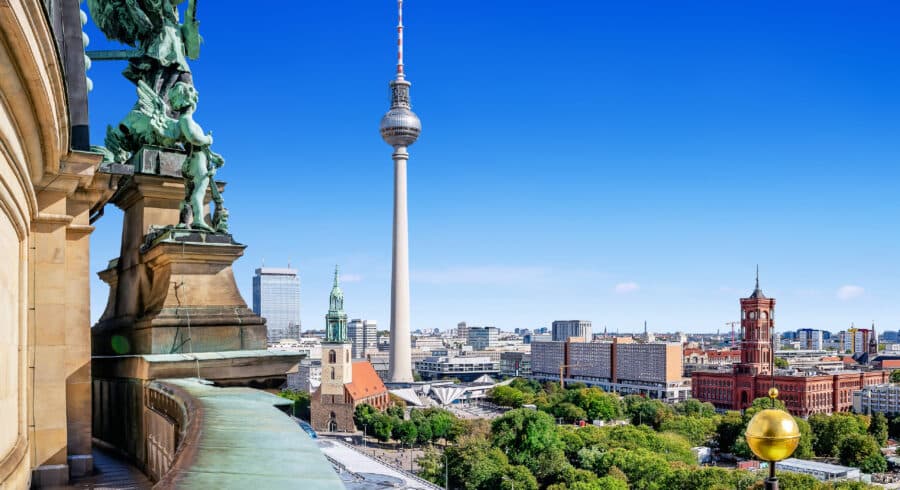View of Berlin cityscape featuring the Berlin TV Tower, red-brick Rotes Rathaus, and various historic buildings under a clear blue sky.