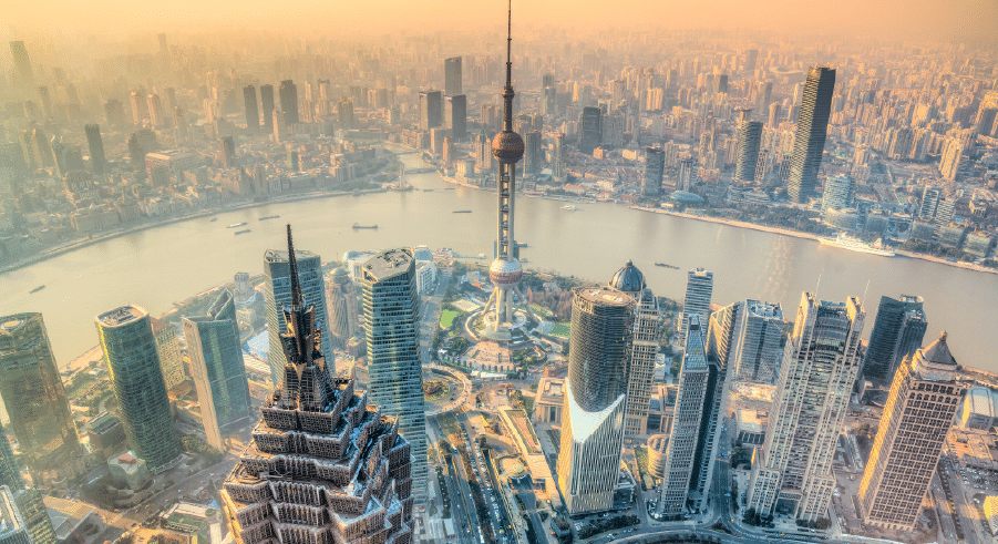Aerial view of Shanghai’s skyline with the Oriental Pearl Tower and modern skyscrapers along the Huangpu River on a hazy day.