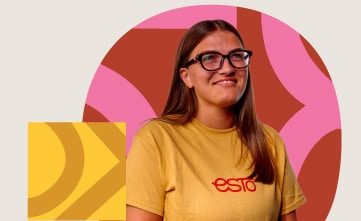 A person with long brown hair and glasses wearing a yellow "esto" T-shirt stands in front of a colourful, abstract background.