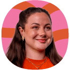 A woman with long brown hair and a red top smiles in front of a pink and orange wavy background.