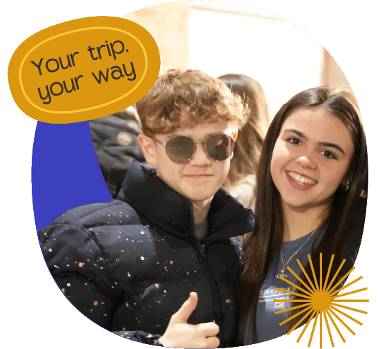 Two young people pose together, one wearing sunglasses and a puffer jacket giving a thumbs up, with the text "Your trip. your way" in a graphic bubble above them.