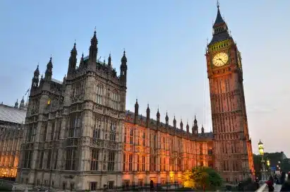 The Houses of Parliament and Big Ben clock tower in London at sunset, with lights illuminating the buildings.