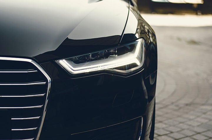 Close-up of an Audi car bonnet with water droplets and light frost, featuring the Audi logo in the centre.