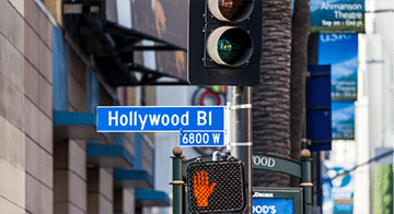 A street sign for Hollywood Blvd and a pedestrian signal showing a red hand at a junction.