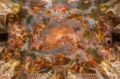 Ornate ceiling fresco shows numerous figures, angels, and clouds in a vibrant, classical style, surrounded by elaborate architectural details and sculptures.