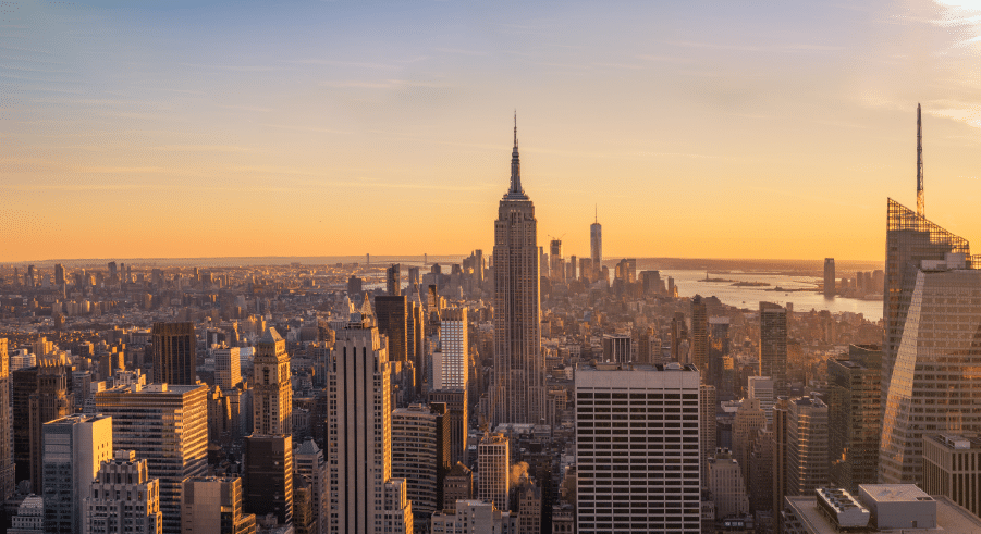 New York City skyline at sunset, featuring the Empire State Building in the centre and various skyscrapers under an orange sky—the perfect view for science trips New York enthusiasts to admire.