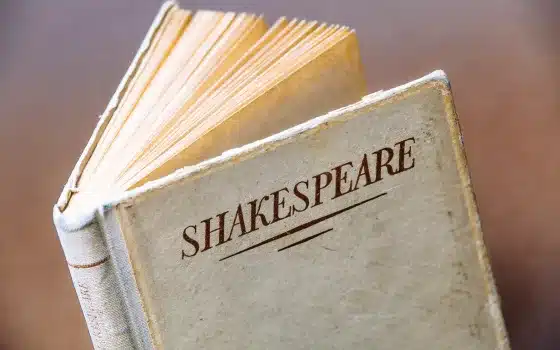An open book with a worn cover displaying the word "Shakespeare" in large, bold letters.