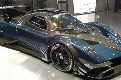 A dark blue Pagani Zonda sports car is displayed indoors, showing its aerodynamic design, sleek curves, and black alloy wheels.