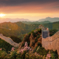 The Great Wall of China stretches across green hills under a sunset sky, with flowering plants in the foreground.