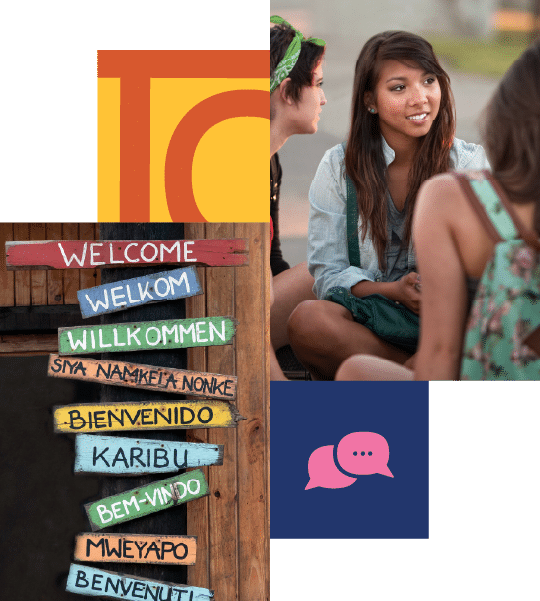 A group of people sits and talks outside; a wooden sign lists 