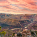 View of the Grand Canyon at sunset with dramatic pink and orange clouds in the sky, a winding river below, and rocky, layered cliffs in the foreground.