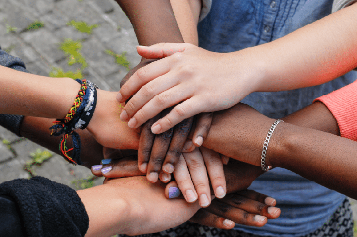 A group of people placing their hands on top of one another to send a message of unity.