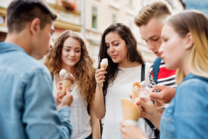 Five young people in a SEND group standing in a circle eating ice cream cornettos.